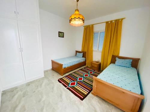 1 dormitorio con 2 camas y lámpara de araña en Un emplacement exceptionnel, en Túnez