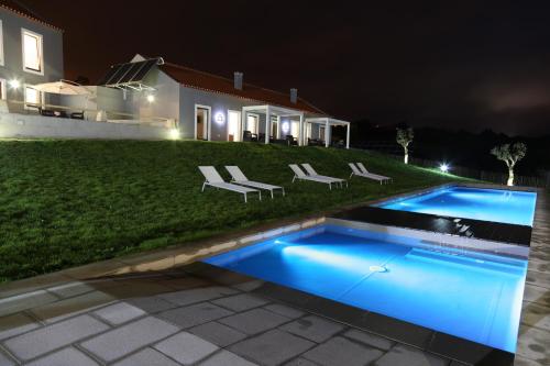 a swimming pool in the yard of a house at night at Casa do Melgaco, Turismo Rural in Casal do Pardo