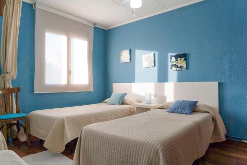 two beds in a room with blue walls at La Pausa Rural & Wellness in Santa Greu del Jutglar