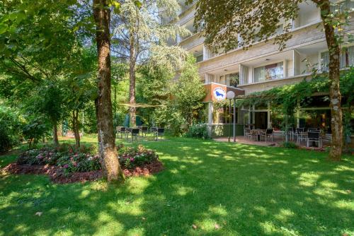 un cortile verde di fronte a un edificio di Hotel Santoli a Porretta Terme