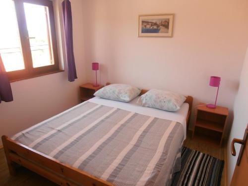 a small bedroom with a bed and two lamps at Vala in Božava