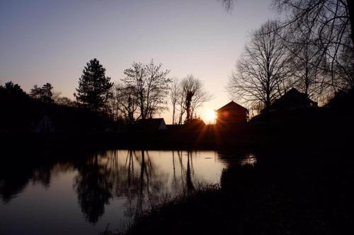 a sunset over a lake with trees and a building at Gästehaus Gerhardt in Schweigen-Rechtenbach