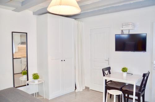 a living room with a table and a tv on a wall at Mon petit chez moi in Chinon