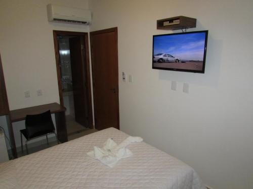 um quarto com uma cama e uma televisão na parede em Hotel Master em Governador Valadares