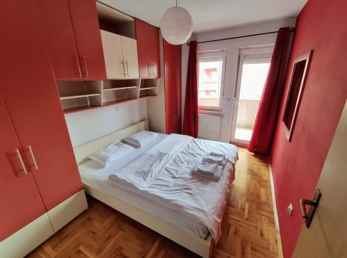 mały pokój z łóżkiem i czerwonymi szafkami w obiekcie Fushe Kosove Apartments w Prisztinie