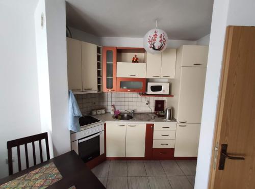 małą kuchnię z białymi szafkami i czerwonymi akcentami w obiekcie Fushe Kosove Apartments w Prisztinie