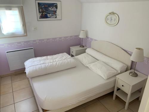 a small bedroom with a white bed and two tables at Gîte du Belvédère in Gérardmer