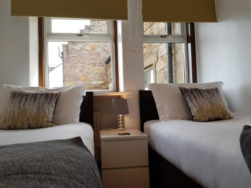 two beds in a room with two windows at Auld Leigh-Lann Apartments in Anstruther