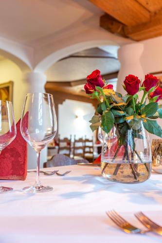 a table with two wine glasses and a vase with roses at Hotel & Restaurant Ritter Jörg in Sommerhausen