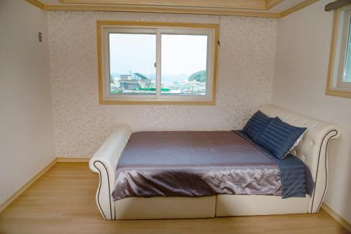łóżko w pokoju z oknem w obiekcie Geoje Blueberry Pension w mieście Geoje