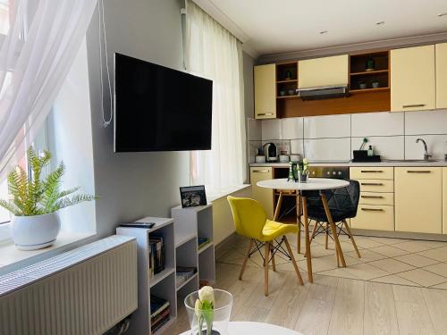 a kitchen with a table and a tv on the wall at Apartament na Starówce III in Pszczyna