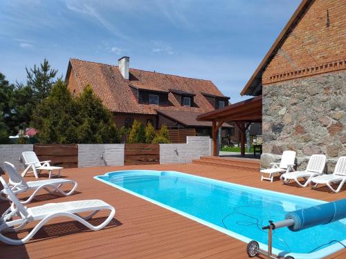 a swimming pool with lounge chairs and a house at Pensjonat pod Kasztanem in Ełk