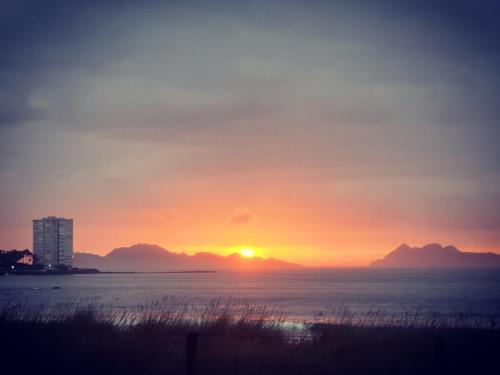 um pôr-do-sol sobre o oceano com montanhas ao fundo em Estudio Vigo Centro Lux em Vigo