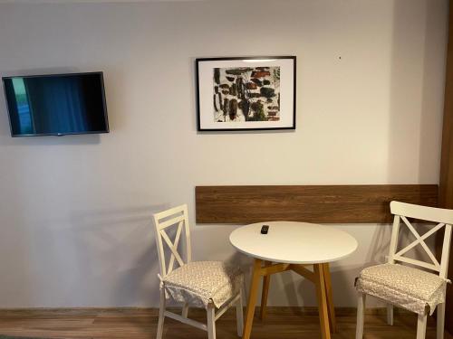 einen Tisch und zwei Stühle sowie einen TV an der Wand in der Unterkunft Apartament CamInSki in Kudowa-Zdrój
