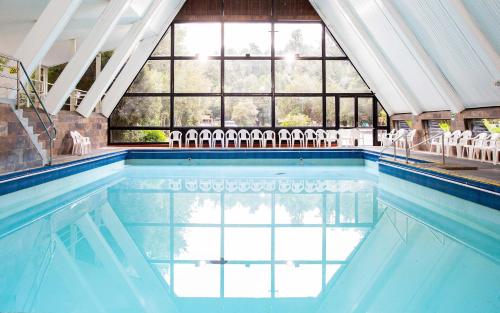a swimming pool with chairs in a building at Termas de Aguas Calientes in Puyehue