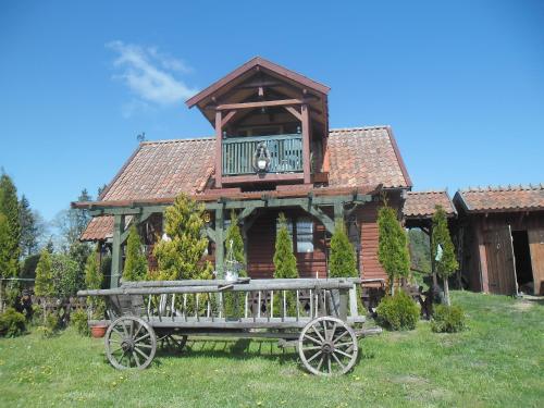 a house with a wooden wagon in front of it at Domek letniskowy Rancho do wynajęcia 7osobowy Rybaczówka in Banie Mazurskie