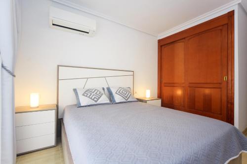 ラ・マンガ・デル・マール・メノールにあるTwo Bedroom Apartment La Mangaのベッドルーム1室(ベッド1台付)、木製キャビネットが備わります。