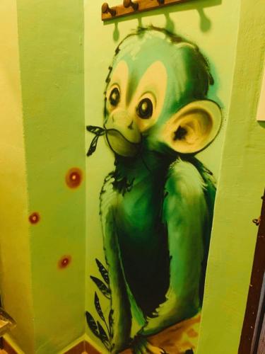 a painting of a green monkey on a wall at Oripando Hostel in Granada