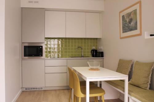a kitchen with white cabinets and a white table and chairs at Cardeal Suites & Apartments in Faro