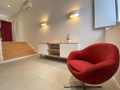 a red chair in a room with a staircase at Cardeal Suites & Apartments in Faro