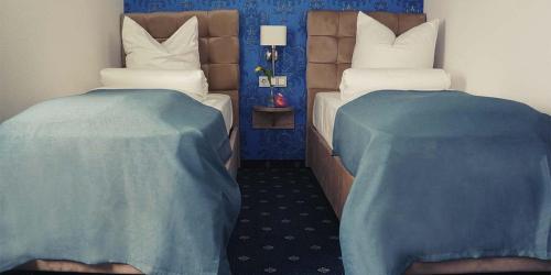 2 Einzelbetten in einem Zimmer mit blauen Wänden in der Unterkunft Arthotel Nagold in Nagold