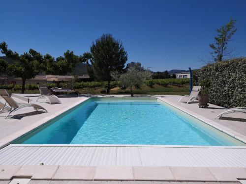 une piscine avec deux chaises et une piscine dans l'établissement Auberge de l Helvie chez Coco & Ricou, à Valvignères