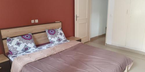 a bed with two pillows on it in a room at Appart Sly Abidjan in Cocody