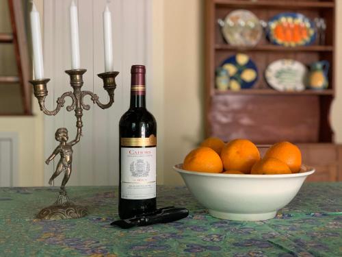 una botella de vino sentada en una mesa junto a un tazón de naranjas en The Stables Gite at Chateau Mas de Pradié, en Foissac