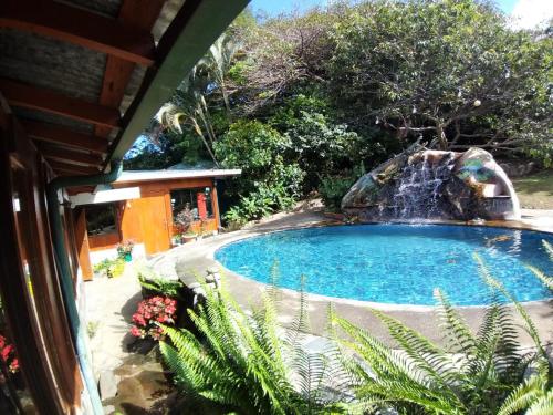 a swimming pool with a waterfall next to a house at Rancho de Lelo Ecolodge in Monteverde Costa Rica