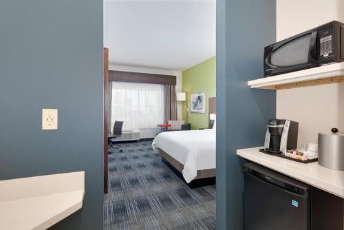 a hotel room with a bed and a tv at Holiday Inn Express & Suites Dallas NW - Farmers Branch by IHG in Farmers Branch