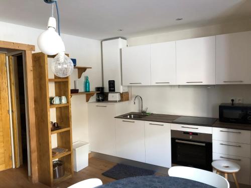 Una cocina con gabinetes blancos y un fregadero. en La Maison De Marie, en Le Monêtier-les-Bains