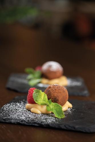 two desserts on a black plate with a strawberry and mint at Elite Plaza Hotel in Gothenburg
