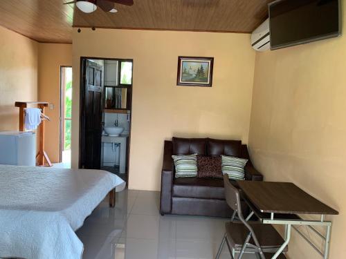 a bedroom with a couch and a bed and a table at Aunty Arenal Lodge in Fortuna