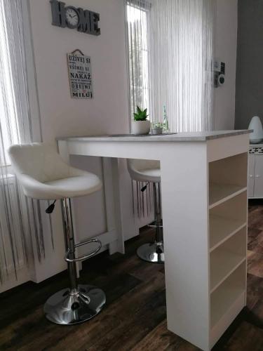 a white kitchen island with two stools and a table at Olsinky in Ústí nad Labem