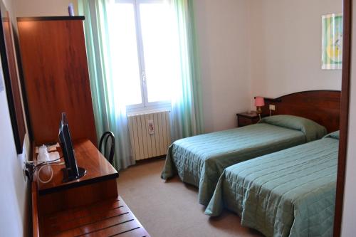 ピアノーロにあるAlbergo Elenaのベッド2台とテレビが備わるホテルルームです。