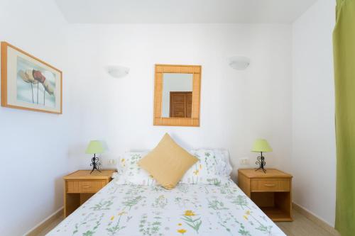 um quarto com uma cama e duas mesas de cabeceira em CASA AMARILLA sunny holiday home with heated pool em San Miguel de Abona
