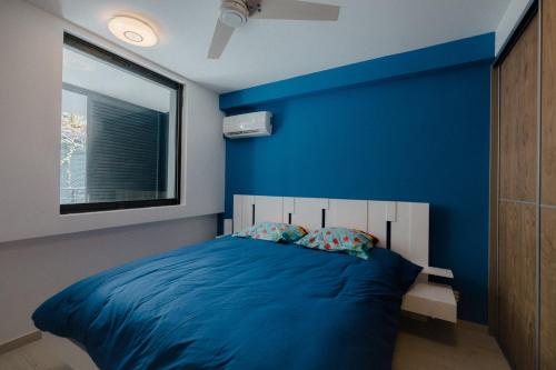 een slaapkamer met een blauwe muur en een bed met kussens bij Perle bleue résidence in Saint-Leu