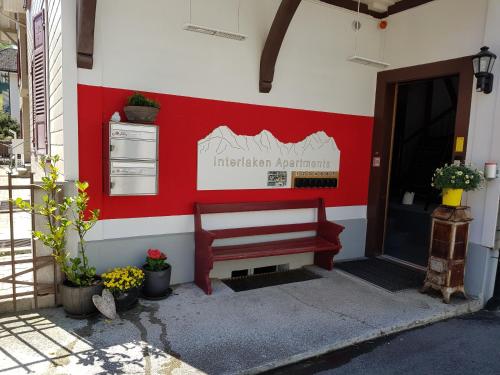 a red and white wall with a bench next to a door at Interlaken Apartments in Interlaken