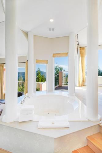 a white bathroom with a tub and windows at Villa Eyrie Resort in Malahat