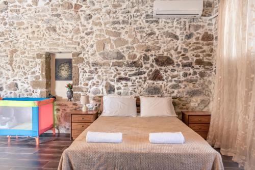 a bedroom with a stone wall and a bed at The Stone House of Iakovos in Kaloudhianá