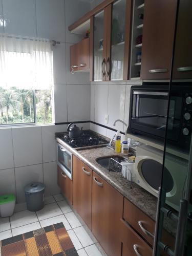 a kitchen with a sink and a microwave at Apto Residencial Saguaçu in Joinville