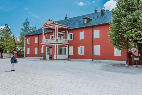 a person standing in front of a large red building at Hotel Dapčević in Cetinje