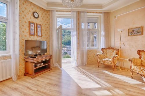 a living room with a television and two chairs at Lyra Apartments in Karlovy Vary