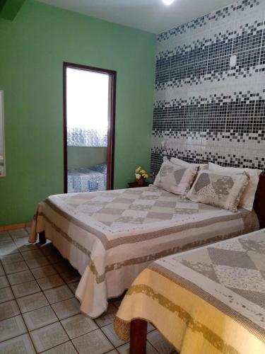 a bedroom with two beds and a window at Pousada Girassol in Rio das Ostras