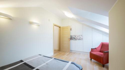 een slaapkamer met een bed en een rode stoel bij Apartament Nadmorski Piasek in Gdańsk