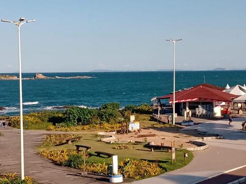 un parque junto al océano con mesas y bancos en Pousada Girassol en Rio das Ostras