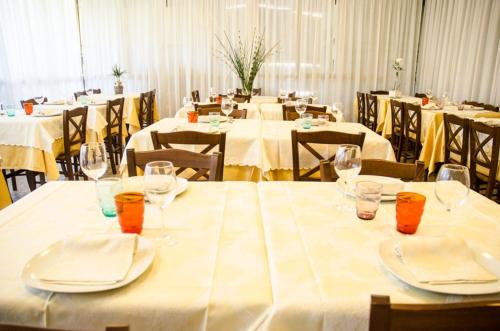 een groep tafels met witte tafelkleden en wijnglazen bij Maison La Vela in Forte dei Marmi