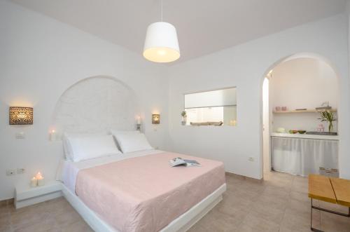 a white bedroom with a large bed and a mirror at Akrolithos studios in Stelida