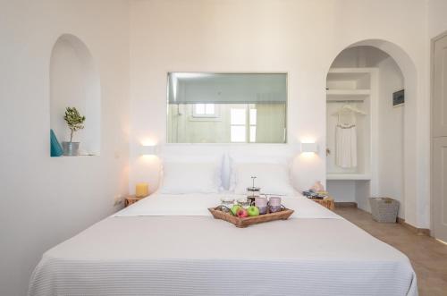 a white bed with a basket of fruit on it at Akrolithos studios in Stelida