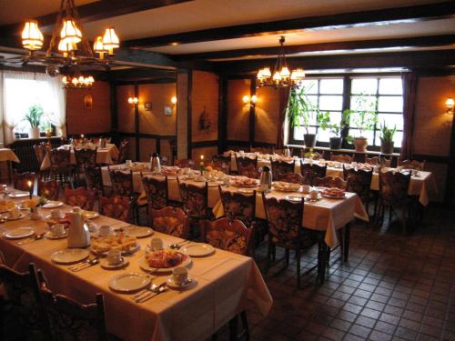 un comedor con muchas mesas, sillas y lámparas de araña en Hotel-Garni Pfeffermühle, en Emmerthal